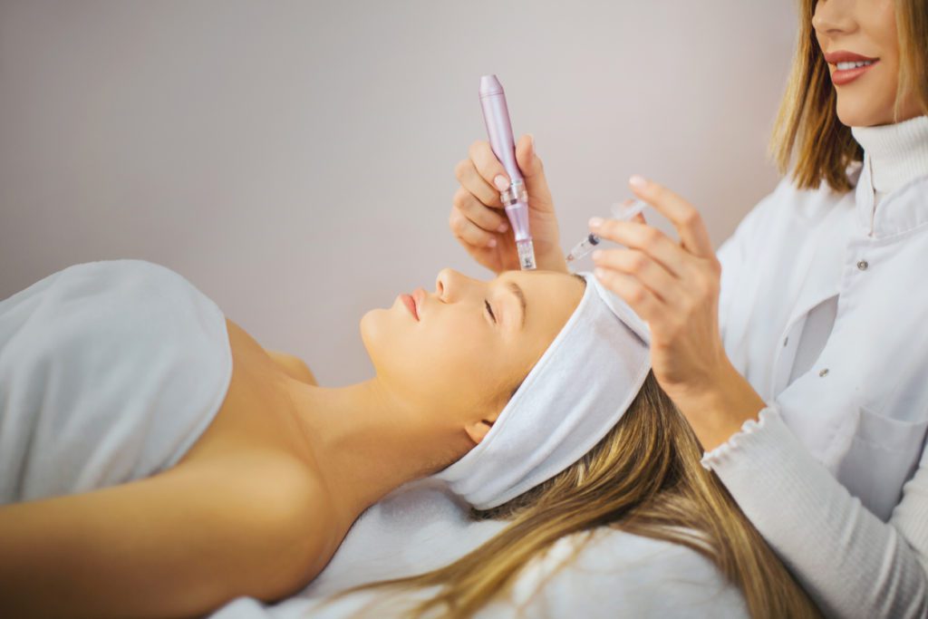 Beautician performs facial treatment on a young woman at beauty salon.