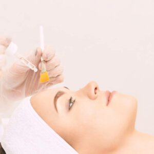 Young woman cleaning face skin in salon. Retinol peel with brush. Acid organic peeling.