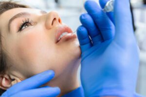 Attractive young woman is getting a rejuvenating facial injections at beauty clinic. The expert beautician is filling female wrinkles by botulinum.