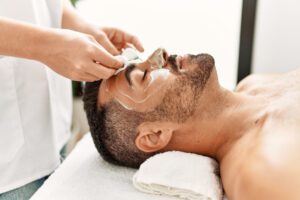 Young man having facial mask treatment at beauty clinic