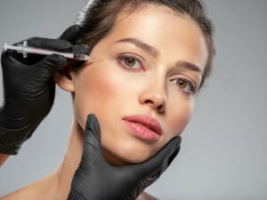 Young caucasian woman getting botox cosmetic injection near the eyes. Beautiful woman gets botox injection in her face. Adult girl gets cosmetic injection of botox in a clinic. Beauty treatments