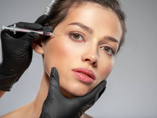 Young caucasian woman getting botox cosmetic injection near the eyes. Beautiful woman gets botox injection in her face. Adult girl gets cosmetic injection of botox in a clinic. Beauty treatments