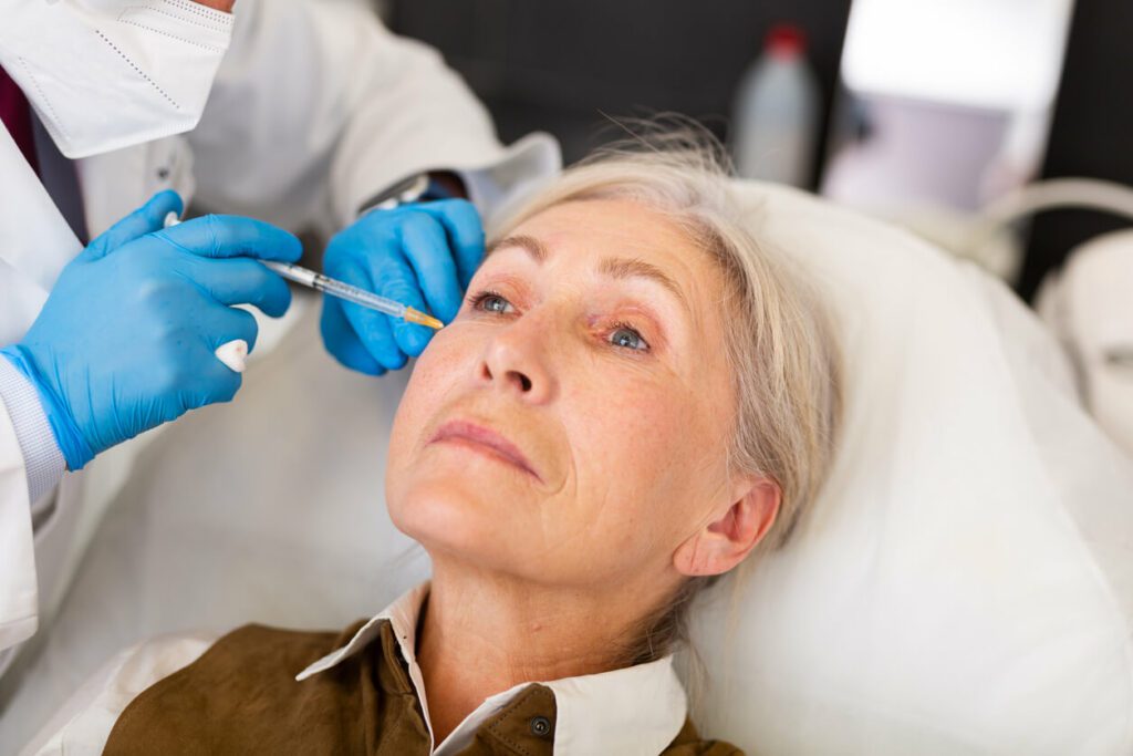 Senior woman receiving face filler injections in med spa