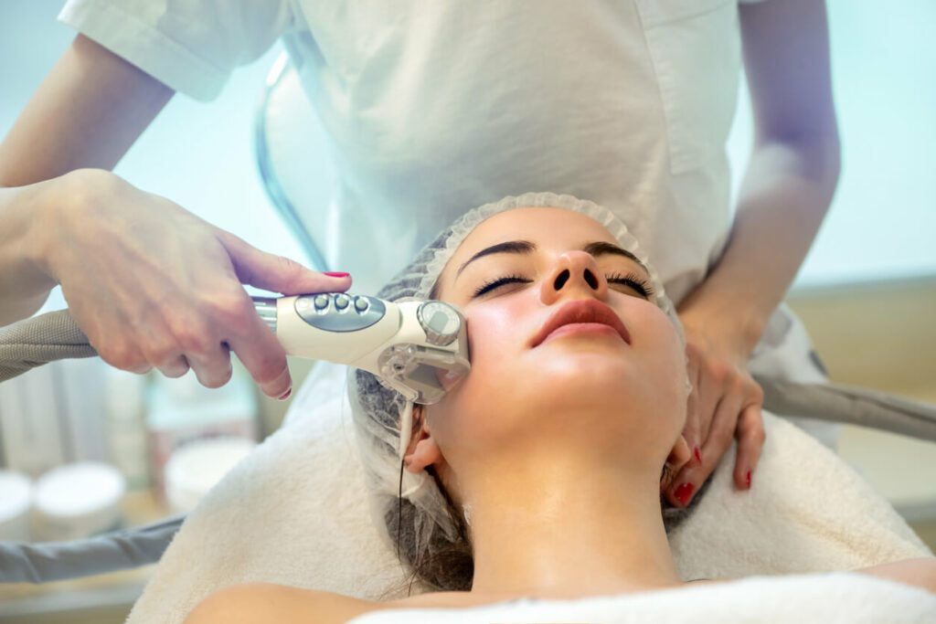 A woman with closed eyes is receiving a facial at a beauty salon in a med spa.