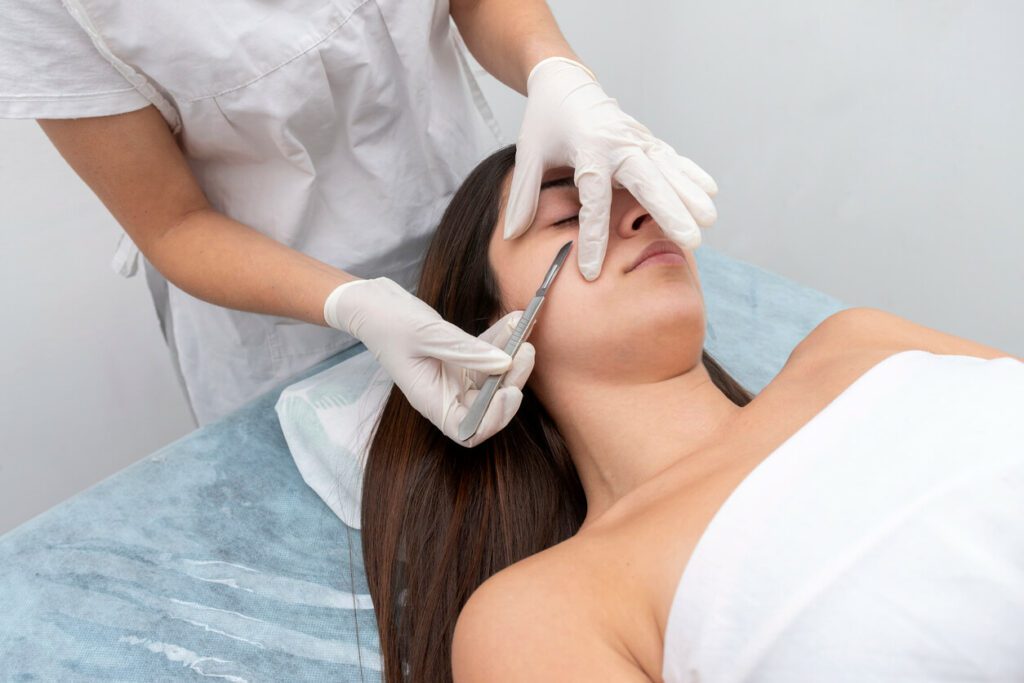 Close-up image of an aesthetician using a scalpel on a woman's skin during a dermaplaning treatment.