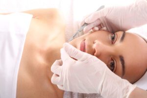 A licensed aesthetician exfoliating the skin with a scalpel during professional dermaplaning.